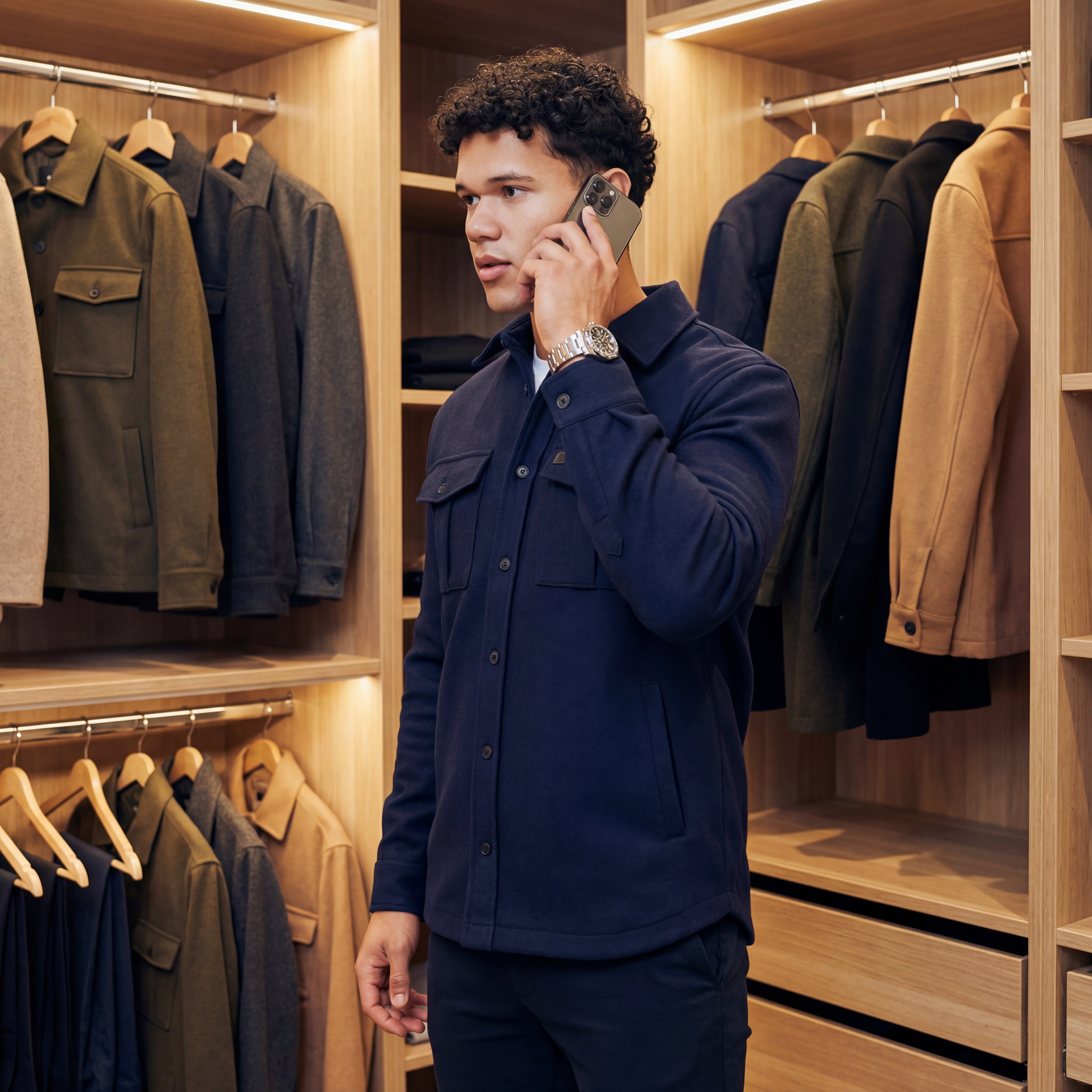 picture of john on the phone, in a closet with wool jackets